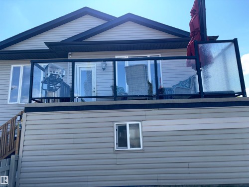 Elevated deck featuring clear glass panel railing with dark framing and a exterior door with decorative glass - 1452 36A Avenue Nw, Edmonton, AB - Outdoor With Exterior