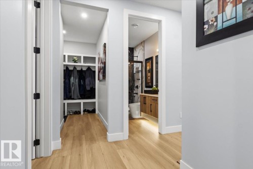 Light wood-finish flooring throughout, a built-in entryway organizer with storage, recessed lighting, and a bathroom featuring a wood-finish vanity and tiled shower surround - 6903 169 Avenue Nw, Edmonton, AB - Indoor Photo Showing Other Room
