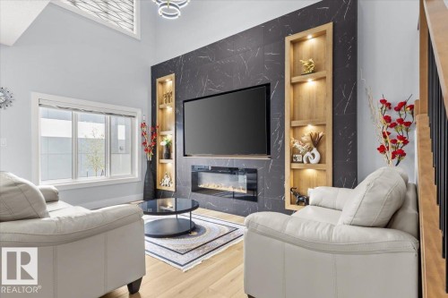 Light wood-finish flooring with a multi-pane window - 6903 169 Avenue Nw, Edmonton, AB - Indoor Photo Showing Living Room With Fireplace