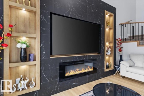 Feature wall with dark-toned, veined paneling, integrated linear fireplace, and recessed display shelving with accent lighting - 6903 169 Avenue Nw, Edmonton, AB - Indoor Photo Showing Living Room With Fireplace