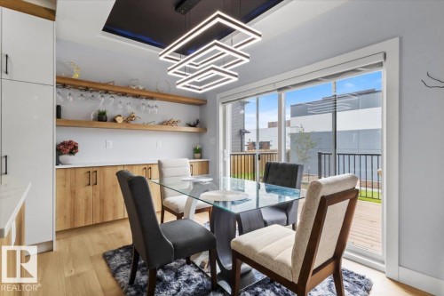 Wood-finish flooring, built-in shelving, white cabinetry, integrated wine glass rack, and a sliding glass door - 6903 169 Avenue Nw, Edmonton, AB - Indoor Photo Showing Dining Room