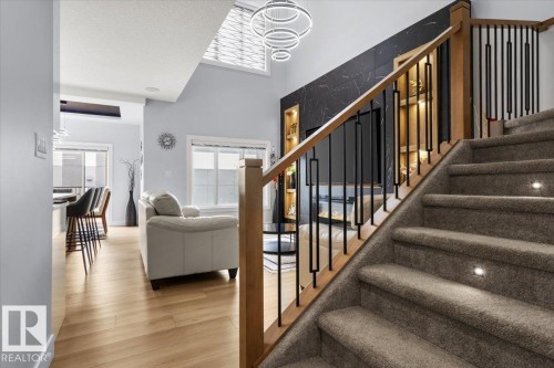 Carpeted staircase with integrated step lighting, light wood-finish flooring, and a contemporary light fixture - 6903 169 Avenue Nw, Edmonton, AB - Indoor Photo Showing Other Room