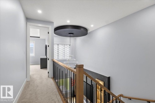 Carpeted hallway with a modern multi-ring pendant light and recessed lighting - 6903 169 Avenue Nw, Edmonton, AB - Indoor Photo Showing Other Room