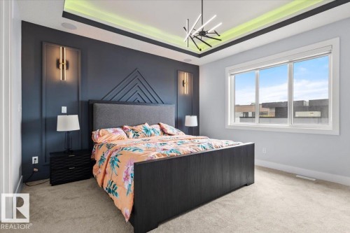 Recessed lighting in tray ceiling, statement chandelier, textured accent wall, integrated wall sconces, triple-pane window - 6903 169 Avenue Nw, Edmonton, AB - Indoor Photo Showing Bedroom