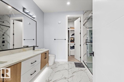 Vanity with integrated lighting, a stone-finish countertop, and undermount sinks - 6903 169 Avenue Nw, Edmonton, AB - Indoor Photo Showing Bathroom