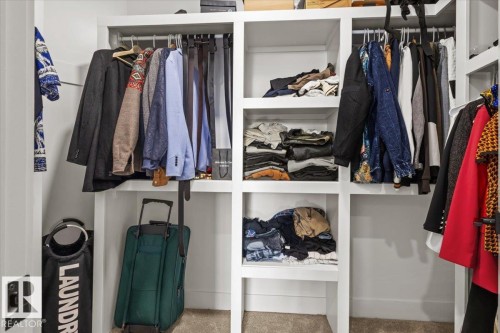 Built-in white shelving system with multiple hanging rods and integrated storage compartments - 6903 169 Avenue Nw, Edmonton, AB - Indoor With Storage