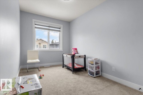 Carpeted room with a large window featuring white trim - 6903 169 Avenue Nw, Edmonton, AB - Indoor
