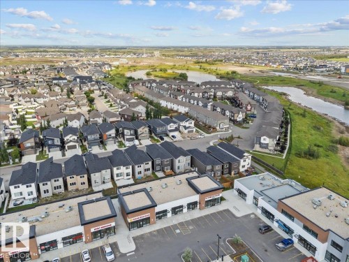 Aerial perspective of a developed residential area featuring a variety of housing styles, commercial buildings with storefronts, and natural water features - 6903 169 Avenue Nw, Edmonton, AB - Outdoor With View