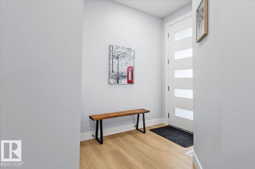 Wood-finish flooring, white walls, and a white entry door with frosted glass panels - 6903 169 Avenue Nw, Edmonton, AB - Indoor Photo Showing Other Room
