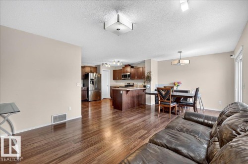 Wood-finish flooring throughout, with a kitchen island, stainless steel appliances, and a dedicated dining area featuring a modern chandelier - 1529 26 Ave Nw Nw, Edmonton, AB - Indoor Photo Showing Living Room