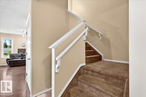 Staircase with brown carpeted treads and white handrails - 1529 26 Ave Nw Nw, Edmonton, AB - Indoor Photo Showing Other Room