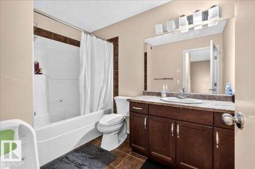 White shower-tub combination with dark tile surround accent - 1529 26 Ave Nw Nw, Edmonton, AB - Indoor Photo Showing Bathroom