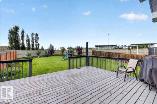 Expansive backyard featuring a large wood-finish deck with dark railings, a manicured lawn, and perimeter fencing - 1529 26 Ave Nw Nw, Edmonton, AB - Outdoor With Deck Patio Veranda