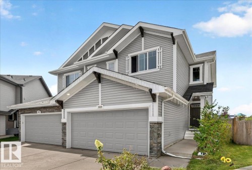 Siding exterior with decorative window framing, stone accents, two-car garage, and dark entrance door - 1529 26 Ave Nw Nw, Edmonton, AB - Outdoor