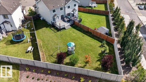Expansive fenced backyard with a wood deck, manicured lawn, and mature trees - 1529 26 Ave Nw Nw, Edmonton, AB - Outdoor