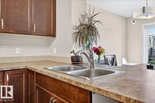 Kitchen featuring wood-finish cabinetry, a dual-basin stainless steel sink, and light-toned countertops - 1529 26 Ave Nw Nw, Edmonton, AB - Indoor Photo Showing Kitchen With Double Sink