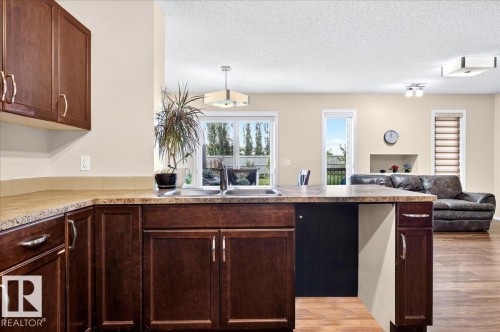 Kitchen featuring dark wood-finish cabinetry, light-colored countertops, and a double basin sink - 1529 26 Ave Nw Nw, Edmonton, AB - Indoor Photo Showing Kitchen With Double Sink