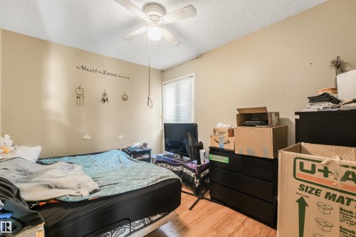 Wood-finish flooring with a ceiling fan light fixture and a single window with blinds - 12209 94 Street Nw, Edmonton, AB - Indoor Photo Showing Bedroom