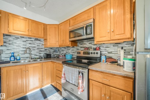 Wood-finish cabinetry with stainless steel hardware - 12209 94 Street Nw, Edmonton, AB - Indoor Photo Showing Kitchen