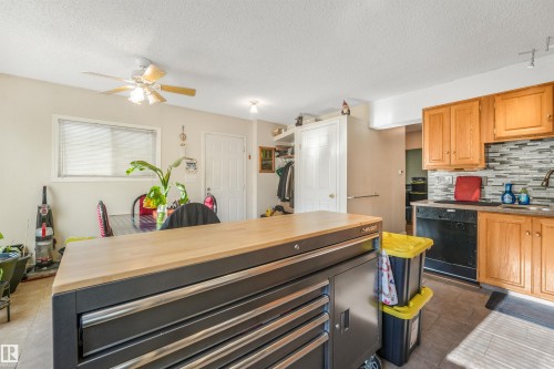 Kitchen featuring wood cabinetry, a tile backsplash, black appliances, and a stainless steel sink with a gooseneck faucet - 12209 94 Street Nw, Edmonton, AB - Indoor Photo Showing Kitchen
