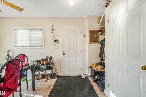 Ceiling fan with wood-finish blades, recessed lighting, double-pane window, and a paneled entry door - 12209 94 Street Nw, Edmonton, AB - Indoor Photo Showing Other Room