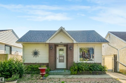 Gabled roofline with asphalt shingles, light-colored siding, brick-clad entry, and a front-facing window - 12209 94 Street Nw, Edmonton, AB - Outdoor