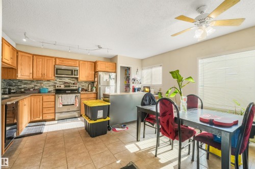 Full kitchen featuring light wood cabinetry, stainless steel appliances, and a mosaic tile backsplash - 12209 94 Street Nw, Edmonton, AB - Indoor Photo Showing Kitchen