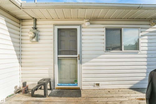 White vinyl siding exterior with a screen door, sliding window, and wooden deck - 12209 94 Street Nw, Edmonton, AB - Outdoor With Exterior