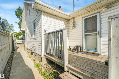 Rear exterior featuring white vinyl siding, a wooden deck, and a privacy fence - 12209 94 Street Nw, Edmonton, AB - Outdoor With Exterior
