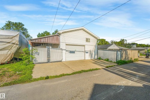 Attached garage with white siding, concrete driveway, and chain-link fencing - 12209 94 Street Nw, Edmonton, AB - Outdoor