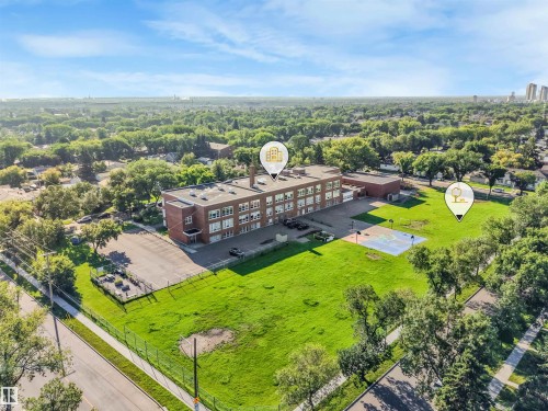 Expansive green space, paved activity court, and mature trees define the exterior - 12209 94 Street Nw, Edmonton, AB - Outdoor With View