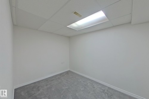 Recessed ceiling paneling with integrated fluorescent lighting, light gray wall paint, and gray carpeting - #7 16823 84 St Nw Nw, Edmonton, AB - Indoor Photo Showing Other Room
