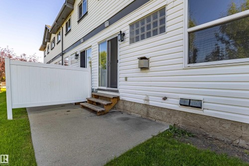Concrete patio with a privacy fence, wood steps, and sliding glass door access - #7 16823 84 St Nw Nw, Edmonton, AB - Outdoor With Exterior
