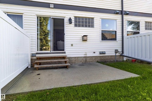 Patio area featuring a sliding glass door, privacy fencing, exterior lighting, and fixed pane windows - #7 16823 84 St Nw Nw, Edmonton, AB - Outdoor With Exterior
