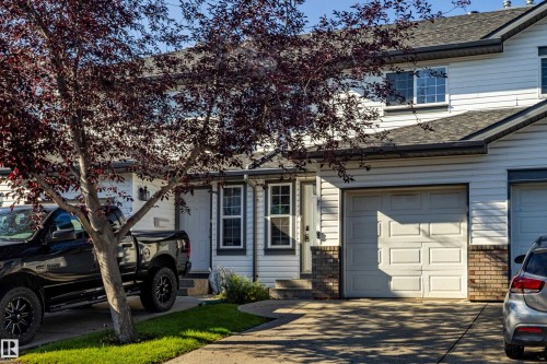 White siding exterior with brick accents, attached garage, and a peaked roofline - #7 16823 84 St Nw Nw, Edmonton, AB - Outdoor With Facade