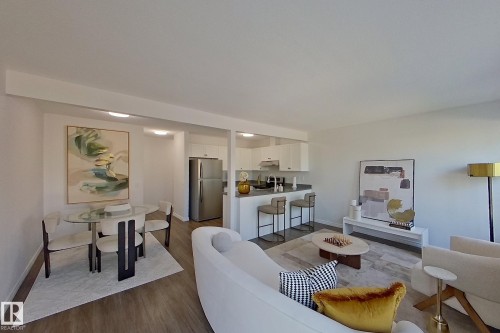 Open-concept living space featuring wood-finish flooring, recessed lighting, and a kitchen with stainless steel appliances, white cabinetry, and a breakfast bar - #7 16823 84 St Nw Nw, Edmonton, AB - Indoor