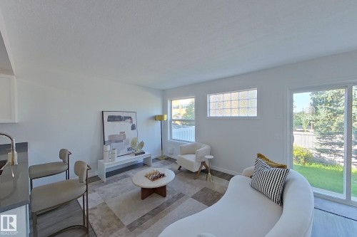 Open-concept living space featuring wood-finish flooring, white walls, multiple windows, and a glass sliding door - #7 16823 84 St Nw Nw, Edmonton, AB - Indoor Photo Showing Living Room