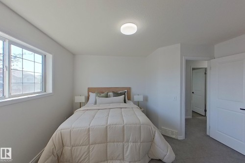 Bright bedroom with white walls, carpet flooring, a multi-pane window, and a flush mount ceiling light - #7 16823 84 St Nw Nw, Edmonton, AB - Indoor Photo Showing Bedroom