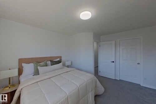 Neutral tone wall paint with white trim, gray carpeting, and a flush-mount ceiling light fixture - #7 16823 84 St Nw Nw, Edmonton, AB - Indoor Photo Showing Bedroom