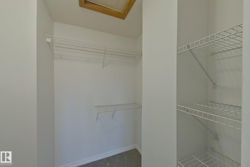 White wire shelving system, integrated hanging rods, and neutral-toned wall paint - #7 16823 84 St Nw Nw, Edmonton, AB - Indoor With Storage