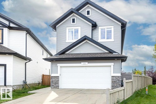 Contemporary exterior with light gray horizontal siding, black trim, a prominent front-facing garage, and a stacked stone accent on the lower facade - 1231 37A Avenue Nw, Edmonton, AB - Outdoor