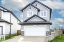 Contemporary exterior with light gray horizontal siding, black trim, a prominent front-facing garage, and a stacked stone accent on the lower facade - 1231 37A Avenue Nw, Edmonton, AB  - Outdoor 