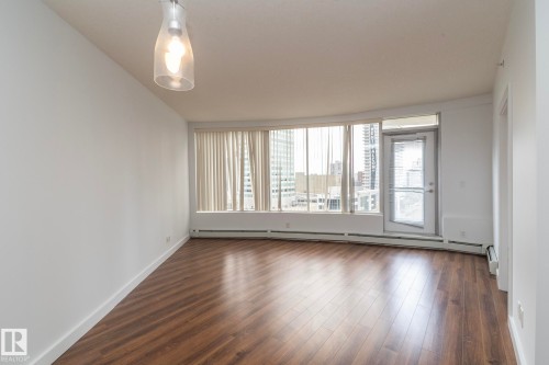 Wood-finish flooring, full-height windows with vertical blinds, and a glass-paneled door - #1004 10136 104 St Nw, Edmonton, AB - Indoor Photo Showing Other Room