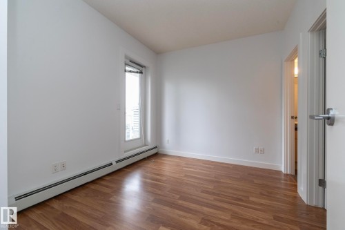 Wood-finish flooring, white walls, and a large window with white trim - #1004 10136 104 St Nw, Edmonton, AB - Indoor Photo Showing Other Room