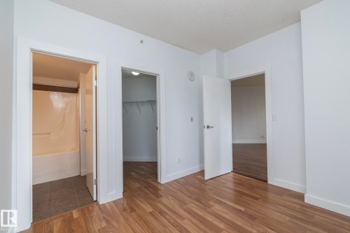 Wood-finish flooring throughout, white interior walls, and multiple doorways leading to additional rooms - #1004 10136 104 St Nw, Edmonton, AB - Indoor Photo Showing Other Room