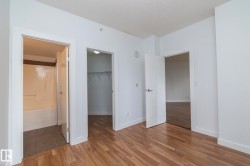Wood-finish flooring throughout, white interior walls, and multiple doorways leading to additional rooms - 