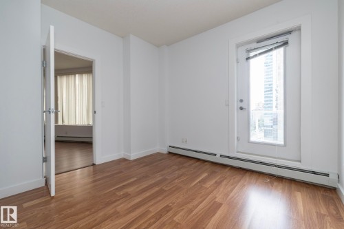 Wood-finish flooring, white painted walls, and a glass-paned door with hardware - #1004 10136 104 St Nw, Edmonton, AB - Indoor Photo Showing Other Room