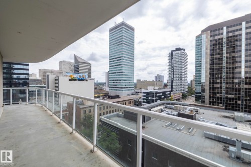 Expansive balcony with concrete flooring, glass panel railing, and cityscape backdrop - #1004 10136 104 St Nw, Edmonton, AB - Outdoor With Balcony