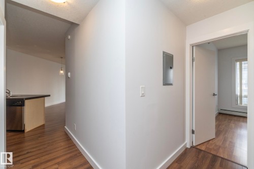 Wood-finish flooring throughout, stainless steel dishwasher, and contemporary pendant light fixture - #1004 10136 104 St Nw, Edmonton, AB - Indoor Photo Showing Other Room