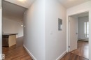 Wood-finish flooring throughout, stainless steel dishwasher, and contemporary pendant light fixture - #1004 10136 104 St Nw, Edmonton, AB  - Indoor Photo Showing Other Room 